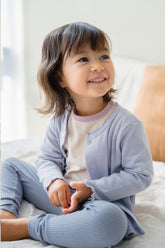 Toddler girl smiling in Avauma Haze Heart Cardigan, soft lavender baby cardigan perfect for cozy everyday outfits.